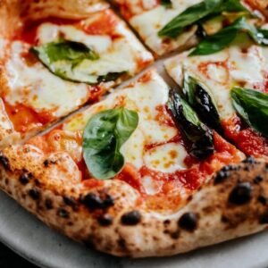 Close-up of a Neapolitan pizza with fresh basil leaves and melted cheese, perfect for food enthusiasts