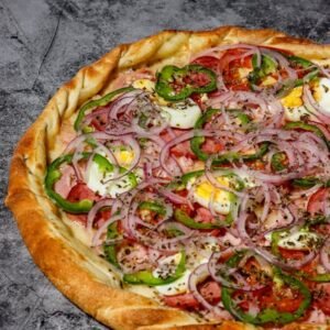 Mouthwatering pizza with fresh bell peppers, onions, and eggs on a marble surface.