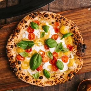 Top view of a delicious Neapolitan pizza with vibrant cherry tomatoes and basil leaves.